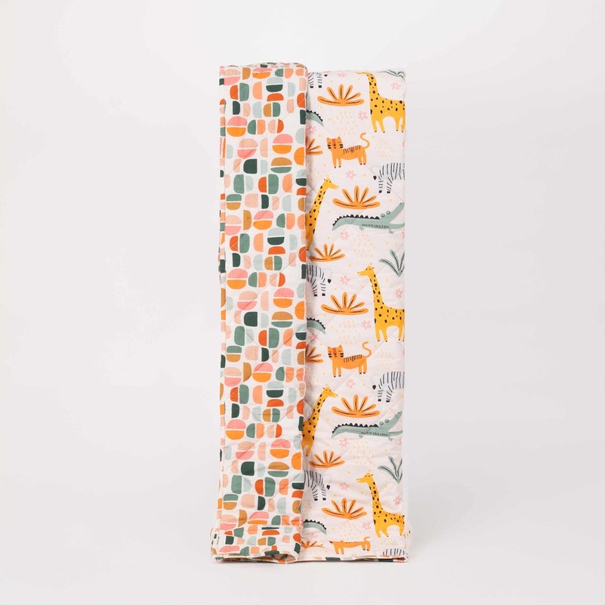 Reversible quilted kids blanket with playful animal print on one side and solid color on the other.