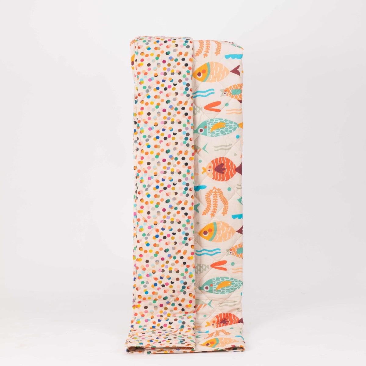 Reversible quilted kids blanket with ocean-themed prints including fish, seaweed, and starfish.