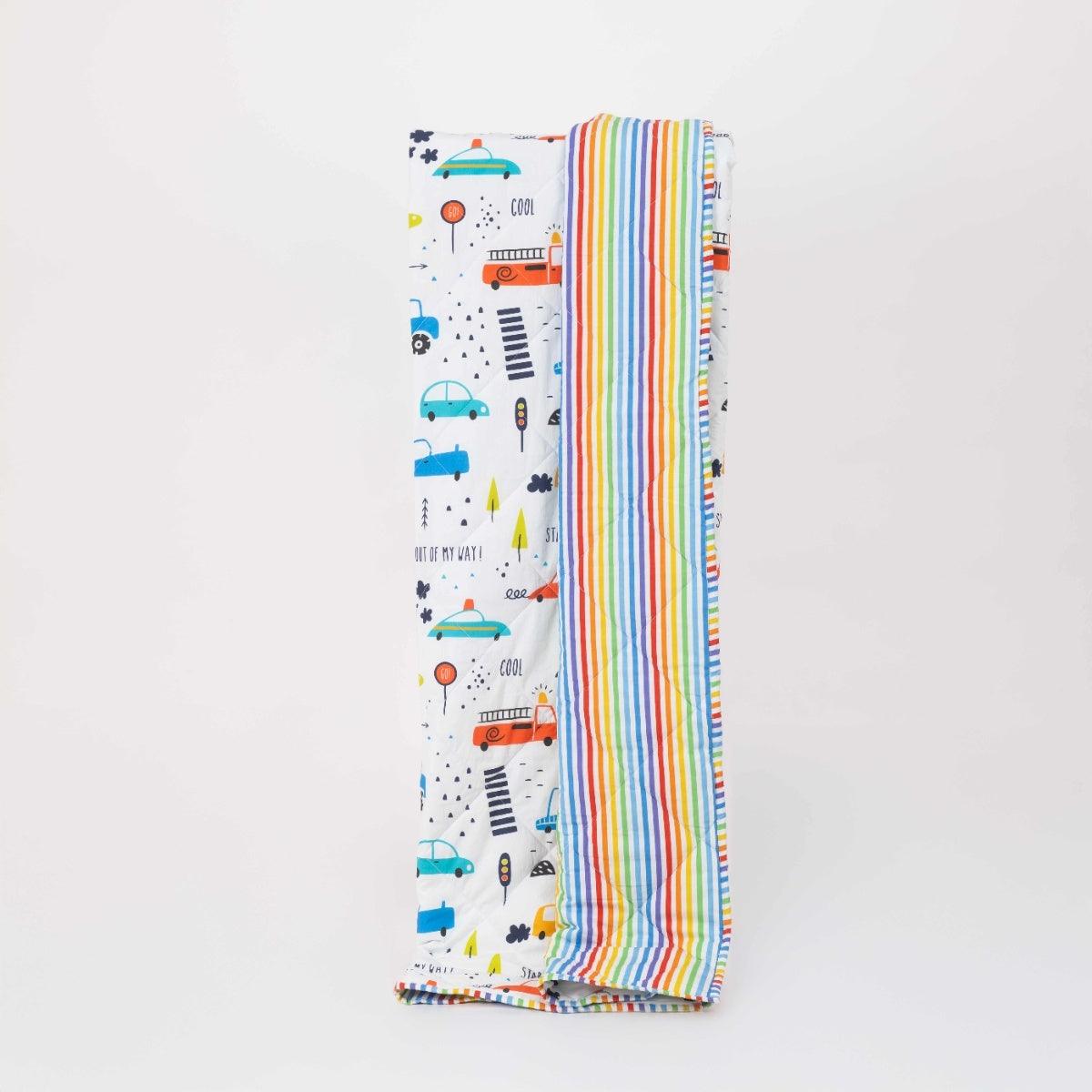Reversible quilted kids blanket featuring transportation-themed prints with cars, buses, and road signs.